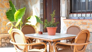 A table with chairs, a potted plant, and a window with bars.