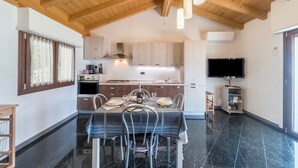 A modern kitchen with wooden beams, a dining table set for four, and a flat-screen TV.
