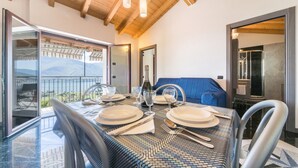 A dining table set for four with a view of the outdoors, a blue sofa, and a wooden ceiling.