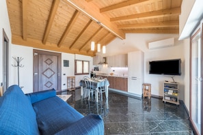 Ein modernes Wohnzimmer mit Sofa, Esstisch, Stühlen, Fernseher und Küchenzeile.