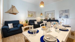 A dining area with a white table set for four, blue plates, and clear glasses. - Vacation Apartment "Appartamento degiorgio8" with Terrace & Wi-Fi (ALGHERO)