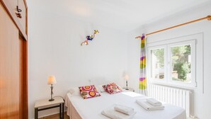 Une chambre d’hôtel avec un lit, deux lampes de chevet, une fenêtre avec des rideaux et un radiateur.