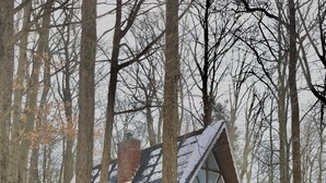 Une cabane aux murs en pierre, dotée d’un balcon en verre et entourée d’un paysage enneigé.
