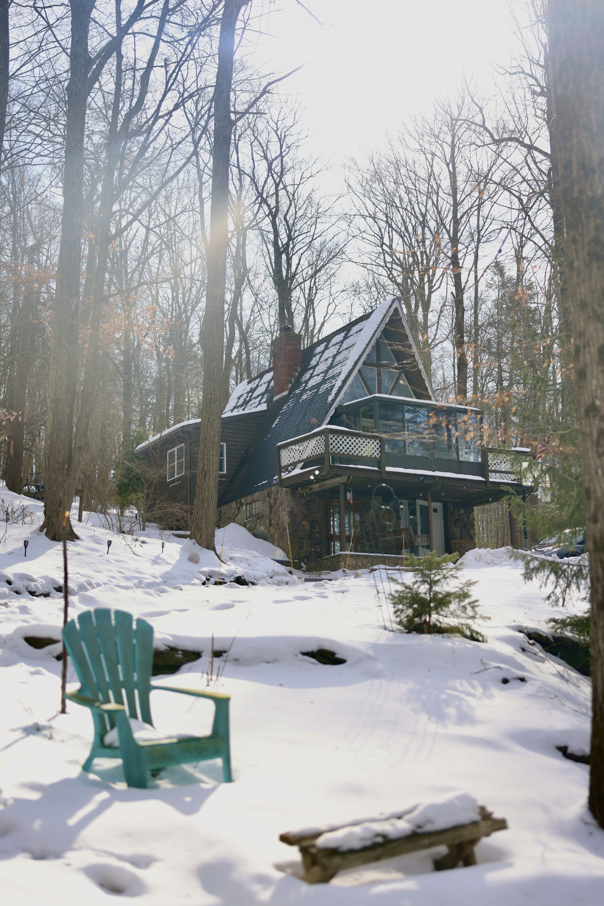 A cabin with a sloped roof, surrounded by snow-covered ground and trees.