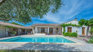 A villa with a swimming pool, outdoor seating, and a garden.