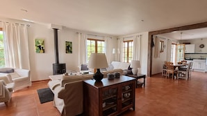 A spacious living area with a fireplace, a dining table, and a kitchen in the background.
