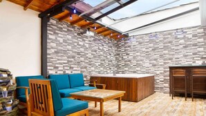 A cozy indoor space with a wooden ceiling, a blue sofa, a wooden table, and a stone-tiled wall. - 3 Bedroom PH Hot Tub Sliding Roof AC (Medellin)