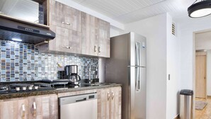 A modern kitchen with wooden cabinets, a stainless steel refrigerator, a coffee maker, and a dishwasher. - 3 Bedroom PH Hot Tub Sliding Roof AC (Medellin)