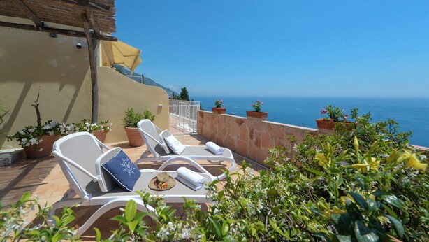 A terrace with white lounge chairs, potted plants, and a view of the sea. - Seaside, near the elevator, just a few steps away, and parking available (Positano)
