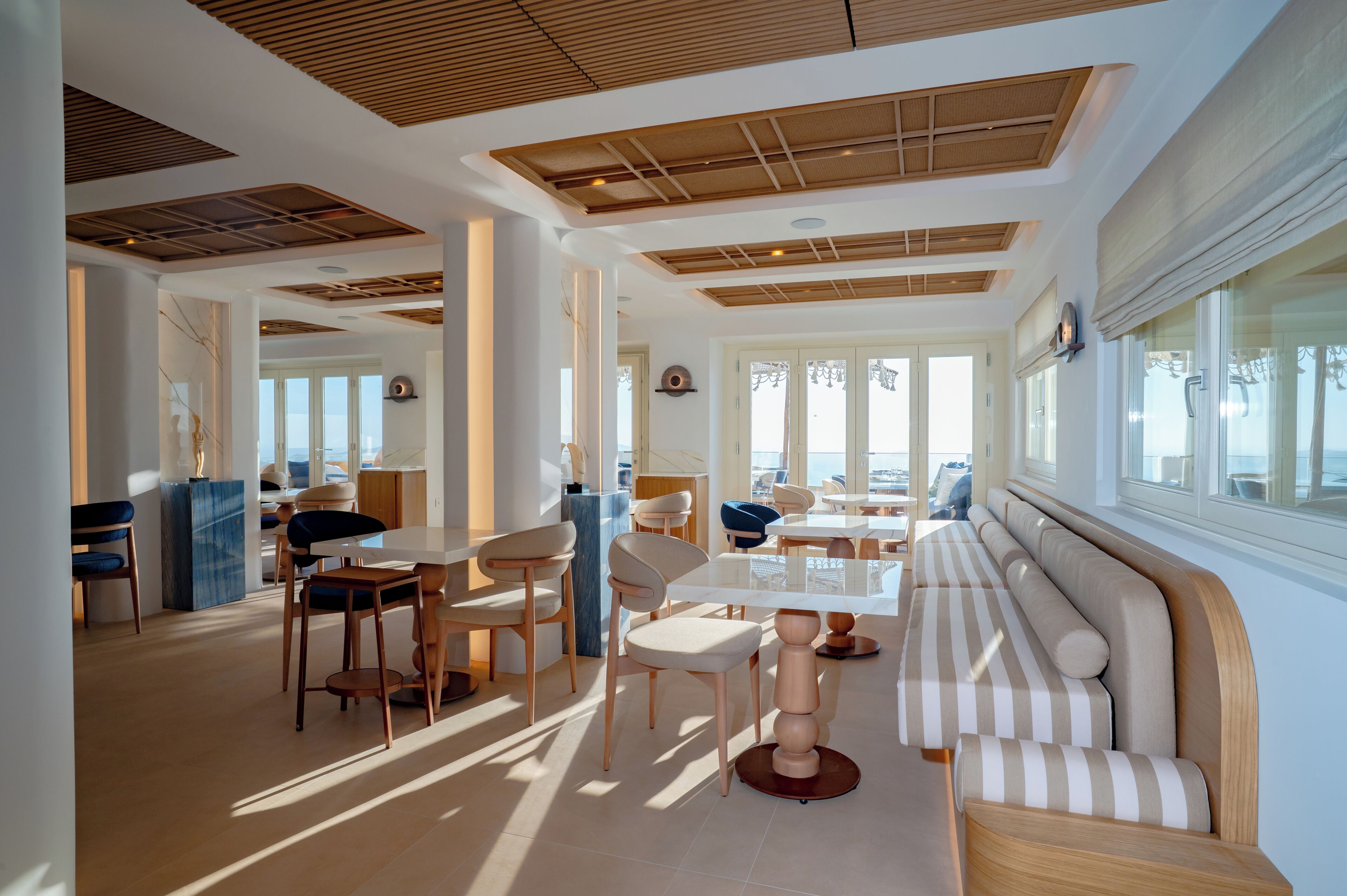 A modern interior with a dining area, seating, and a view through large windows.