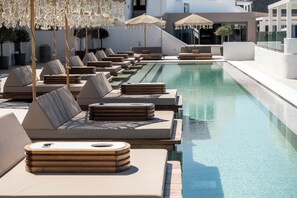 A poolside area with sun loungers, umbrellas, and a clear pool.