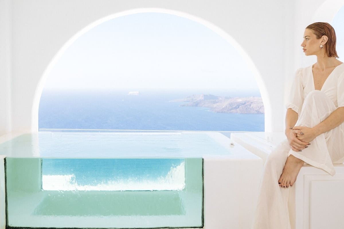 Una persona sentada junto a una ventana con vista al mar.