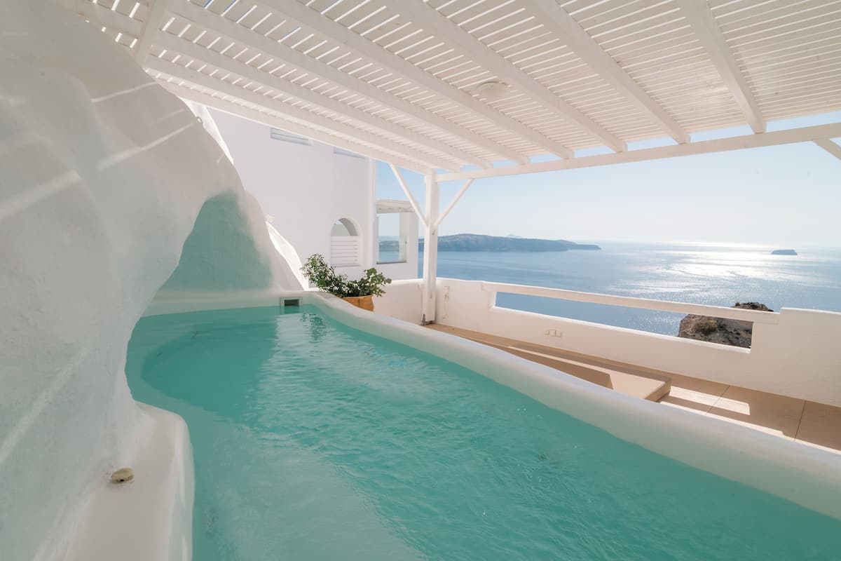 Una piscina con vista al mar y un edificio blanco.