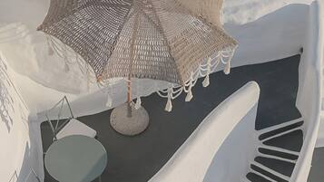 Un área de estar al aire libre y de diseño moderno con una mesa redonda y sillas, un parasol tejido y un diseño de silla único.
