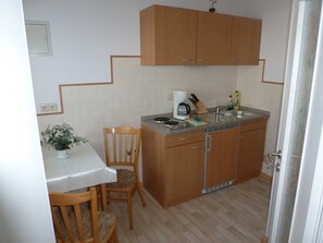 Eine kleine Küche mit Holzausstattung, einer Arbeitsplatte, einer Kaffeemaschine und einem Spülbecken.