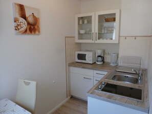 A compact kitchenette with a microwave, coffee maker, and a sink.