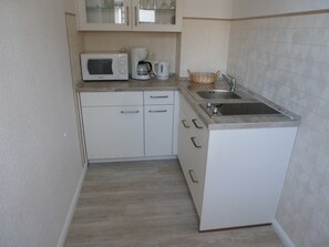 A compact kitchen with a microwave, coffee maker, and a sink.