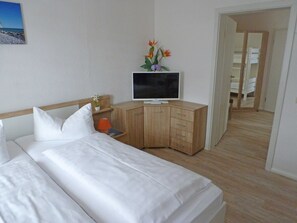 Ein Hotelzimmer mit Bett, Fernseher, einem Holzschrank und einem kleinen Tisch mit Lampe.