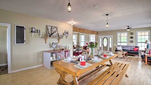 A spacious living area with a wooden dining table, benches, and a cozy seating area with a sofa and armchairs. - Secluded Angler's Haven - Boat + Fish! (Rosston)