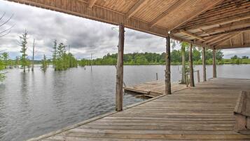 A wooden pier extending into a calm lake, supported by wooden posts, with a covered area overhead.