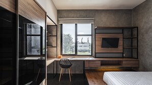 A modern bedroom with a large window, a bed, a desk with a chair, and built-in shelving. - LOA Living Solo Baru (Grogol)