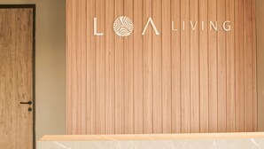 A reception desk with a wooden panel wall and the text "LOA LIVING" above it. - LOA Living Solo Baru (Grogol)