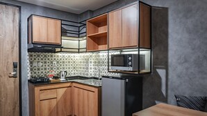 A compact kitchen with wooden cabinets, a microwave, and a stainless steel sink. - LOA Living Solo Baru (Grogol)