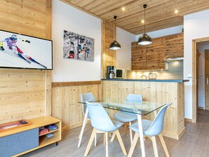 Una cocina moderna con armarios de madera, una mesa de comedor de vidrio y sillas azules.