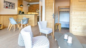 A cozy cabin with a wooden interior, a dining area with chairs, a bunk bed, and a kitchen area with a microwave. - Large Studio Cabin, Balcony, Parking, La Clusaz Center (La Clusaz)