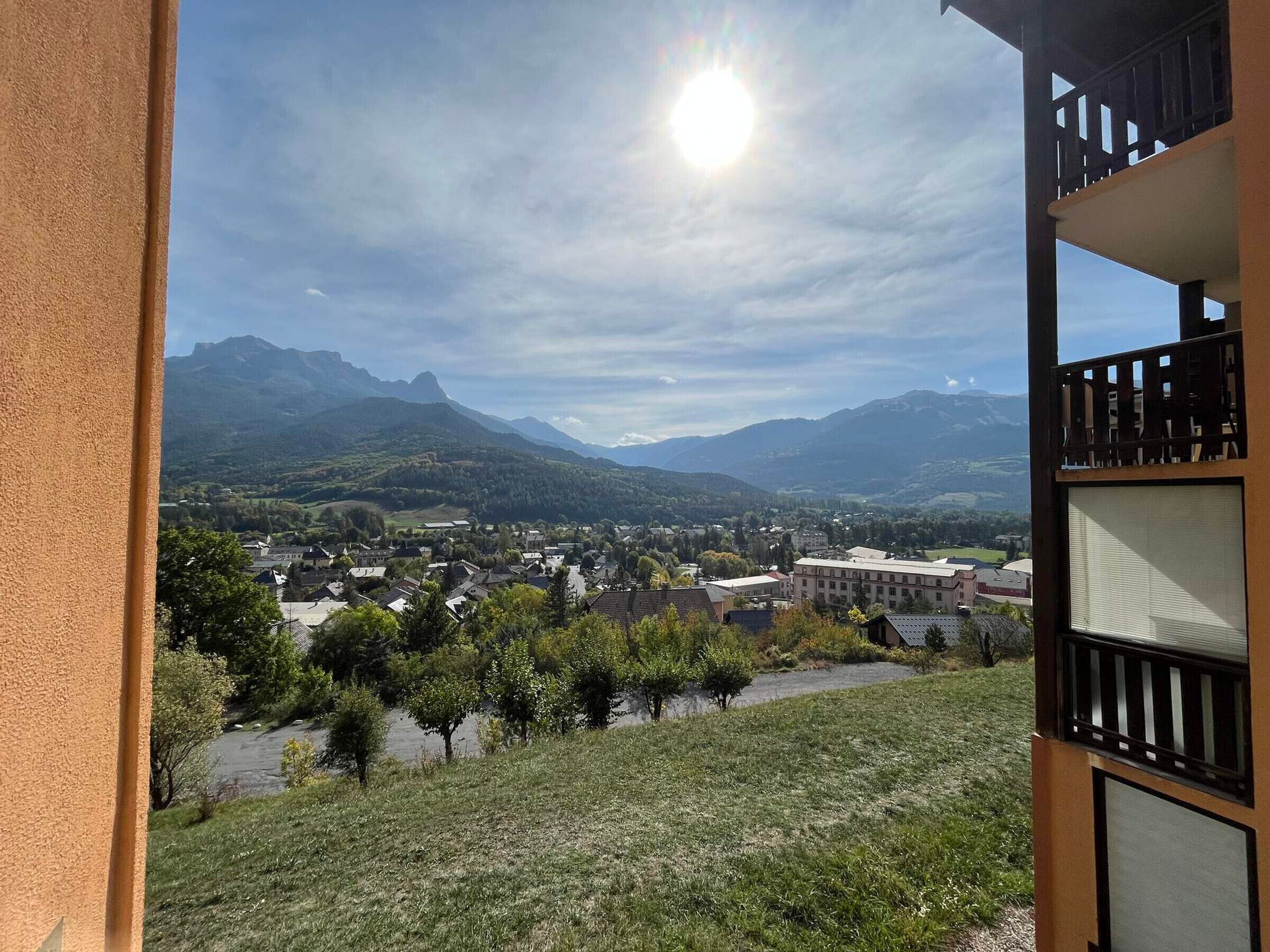 A view from a balcony overlooking a town with mountains in the background.