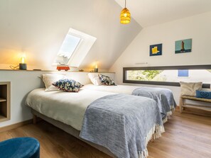 A cozy bedroom with two beds, a skylight, a window, and a hanging light fixture. - Modern Home Near Beach, Private Garden, Terrace, BBQ, Bikes, WiFi - 3BR, 3BA Sleeps 6 (Mesquer)