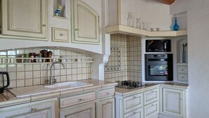 A kitchen with white cabinets, a sink, a stove, and a microwave.