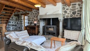A cozy living room with a stone fireplace, a television, and a leather sofa.