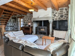 Una sala de estar acogedora con chimenea de piedra, televisor y sofá de cuero.