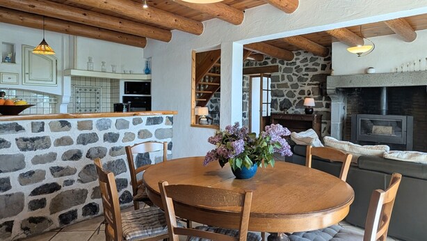 A rustic interior with a stone wall, wooden dining table, and chairs.