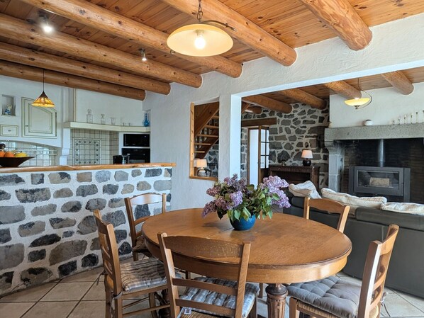 Un interior rústico con pared de piedra, mesa de madera y sillas.