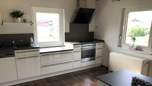 Una cucina moderna con mobili bianchi, un piano cottura nero e una finestra vista giardino.