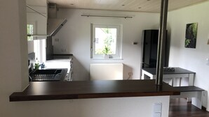 Una cucina moderna con una finestra, una TV nera e un piccolo tavolo.
