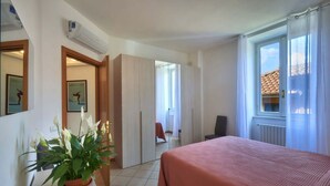 A hotel room with a bed, a potted plant, a desk, and a window with curtains. - Casa Lido beautiful lake view (Varenna)