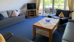 Una sala de estar con un sofá, una mesa de centro y un televisor sobre un mueble.