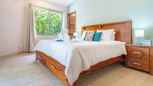Un dormitorio con una cama de madera, una mesita de noche y un ventanal con cortinas.