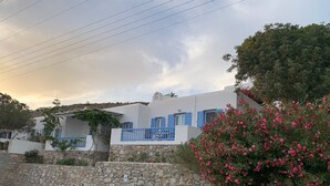 A white building with blue shutters and a stone wall in front. - Ferienwohnung (ΜΥΚΟΝΟΣ)