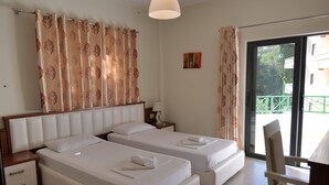 A hotel room with two beds, a nightstand, a chair, and a view of a balcony. - Privé City Hotel (Sarandë)
