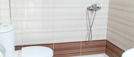 Une salle de bain équipée de toilettes, d’un bidet et d’un espace douche.