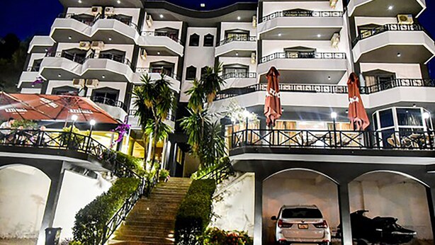 A multi-story hotel with balconies, a covered walkway, and a parking area. - Privé City Hotel (Sarandë)