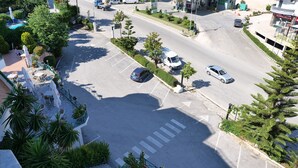 An aerial view of a parking lot with multiple cars, a gas station, and a building with a green roof. - Privé City Hotel (Sarandë)