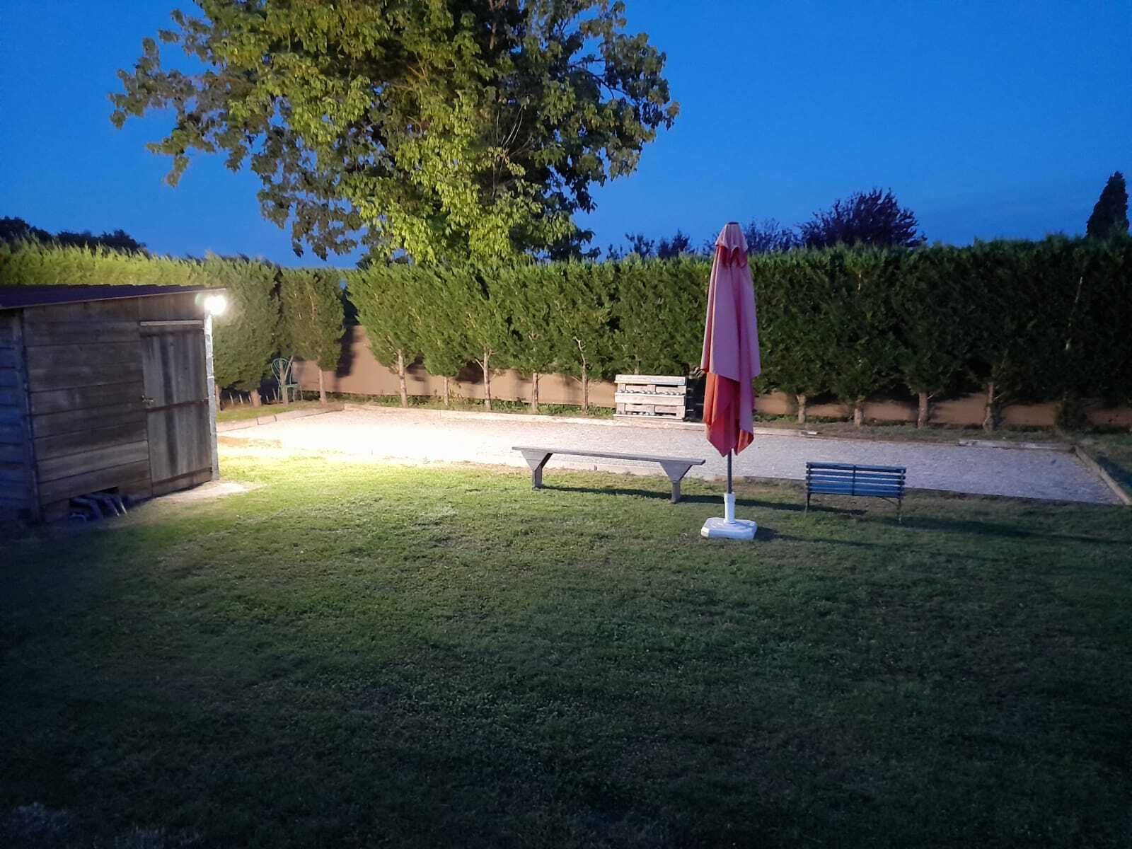 A well-lit outdoor area with a picnic table, a bench, and a covered seating area.