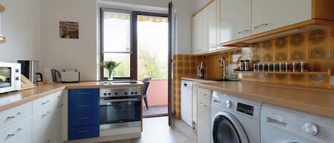 Una cocina compacta con horno integrado, lavadora y cafetera.