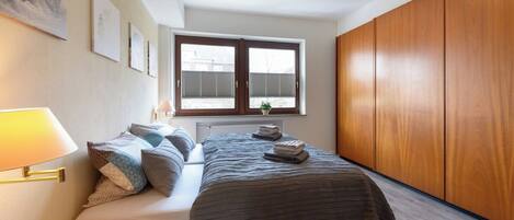 A bedroom with a bed, a window, and a radiator.