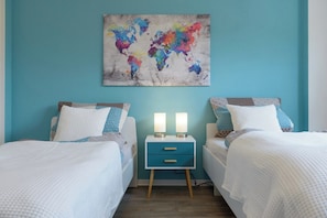 Une chambre avec deux lits, une table de chevet dotée de deux lampes et une œuvre d’art représentant une carte du monde accrochée au mur.